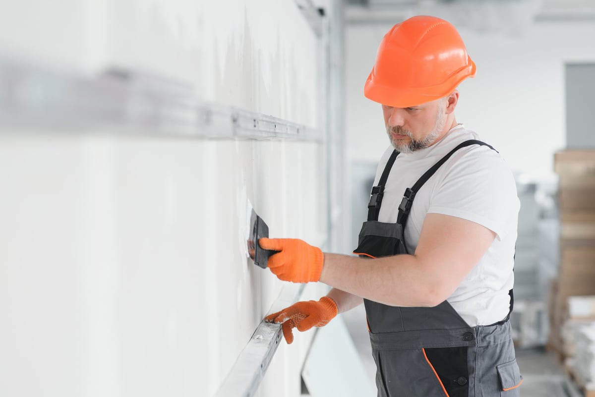 Drywall finisher applying mesh tape to a plasterboard wall