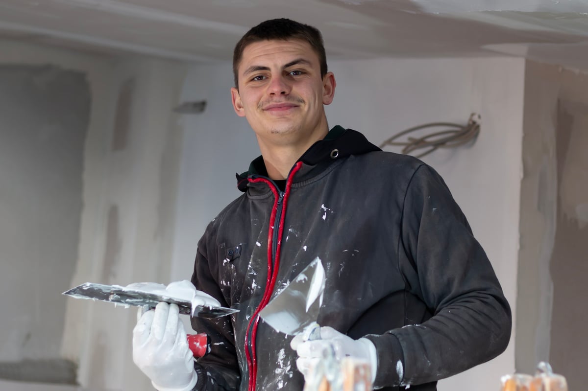 Builder smoothing putty plaster across a ceiling