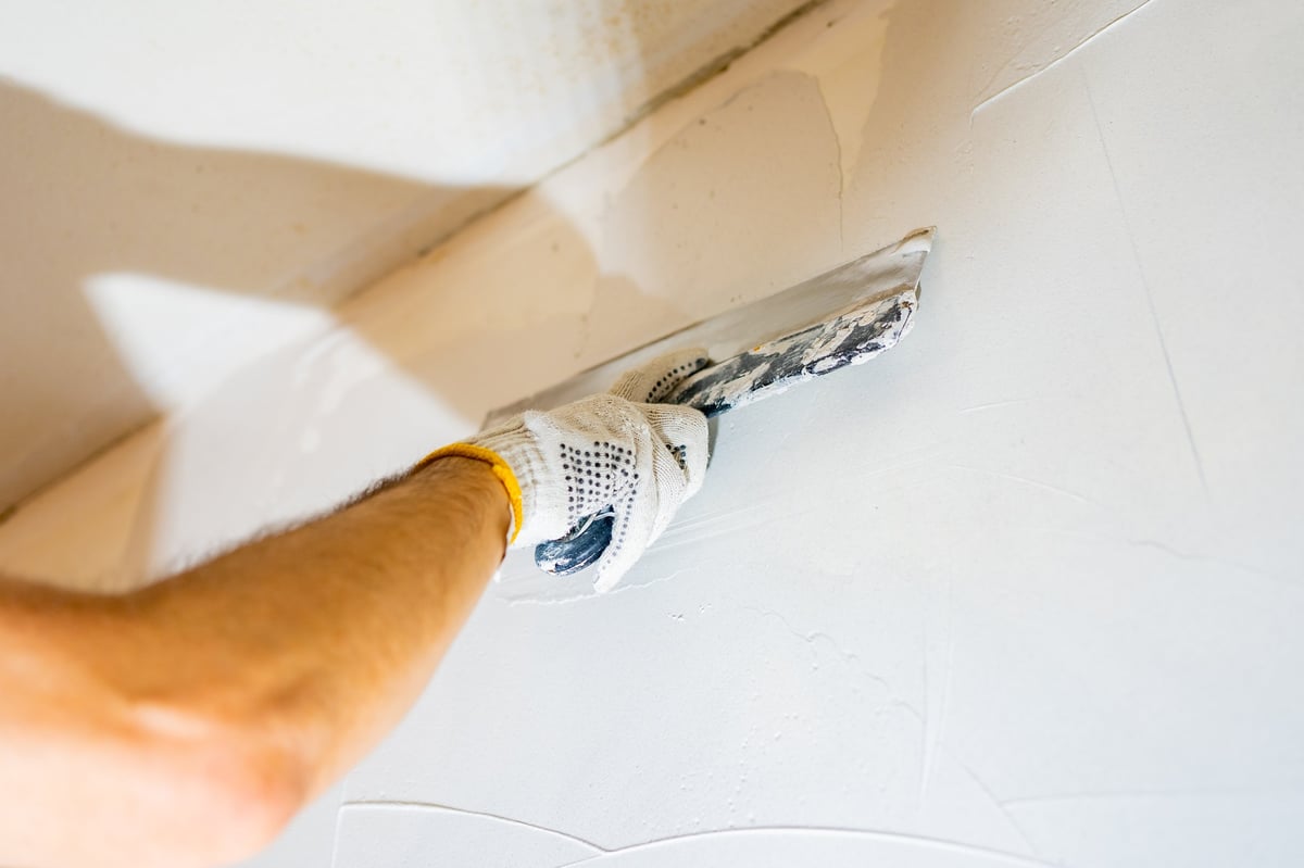 Worker smoothly applying drywall mud to a wall surface